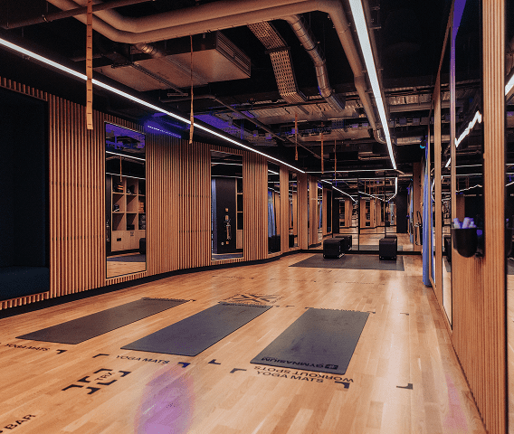 A wooden gym with mirrors and white lights and yoga mats on the floor