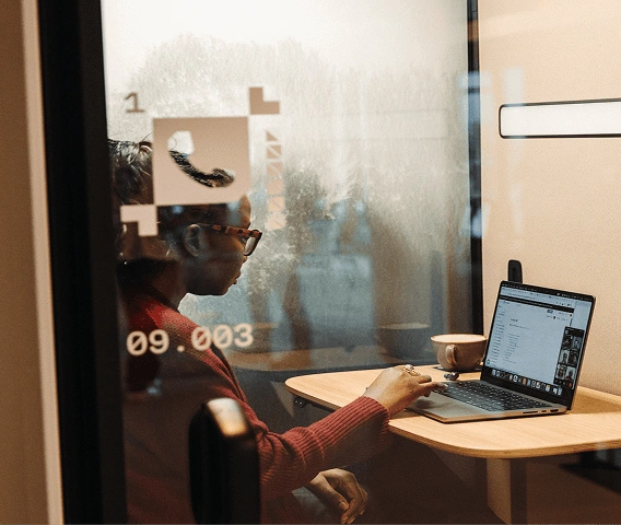 A woman in an individual work pod looking down at her laptop.