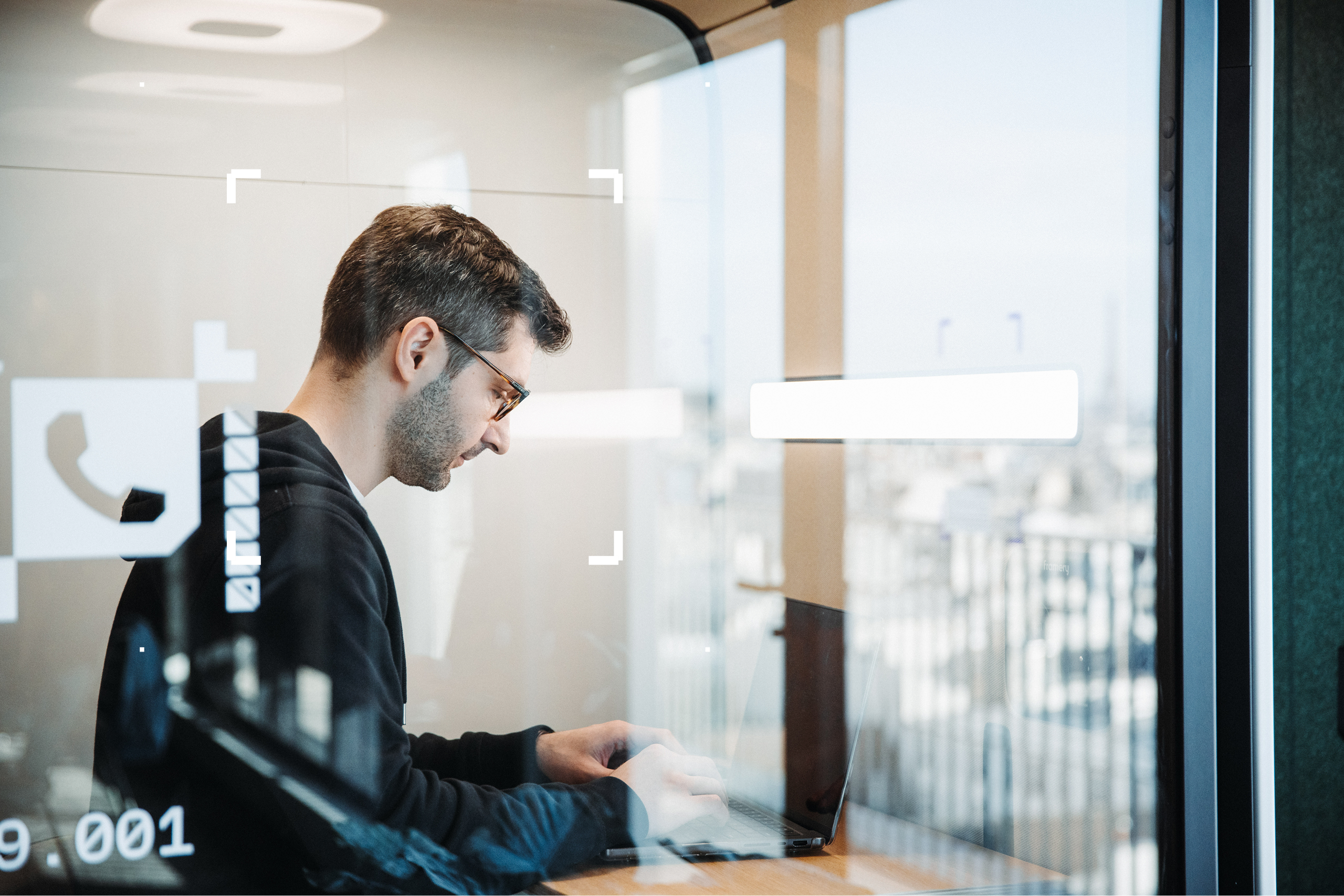 Man sitting in a work pod on his own looking down at his laptop