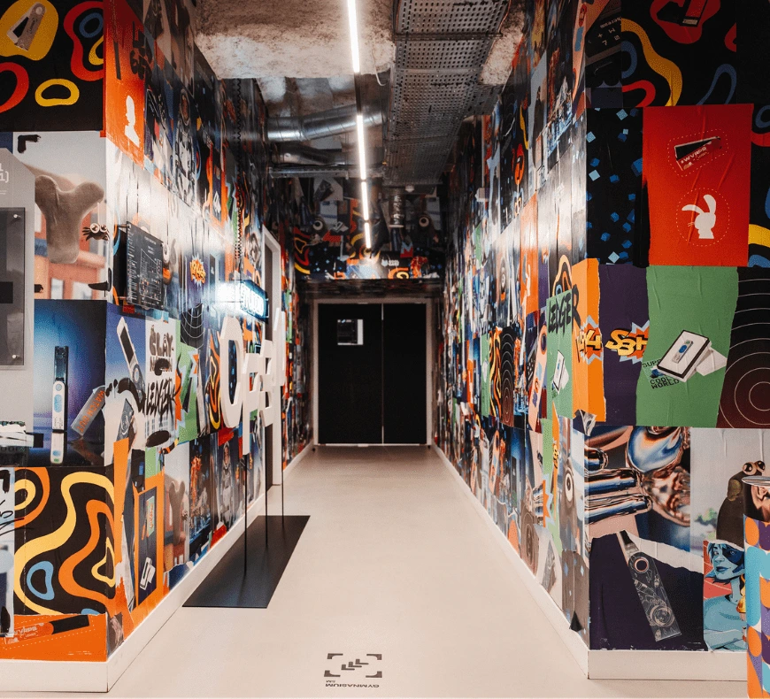 A colourful office corridor lined with vibrant artwork and illuminated by overhead lighting