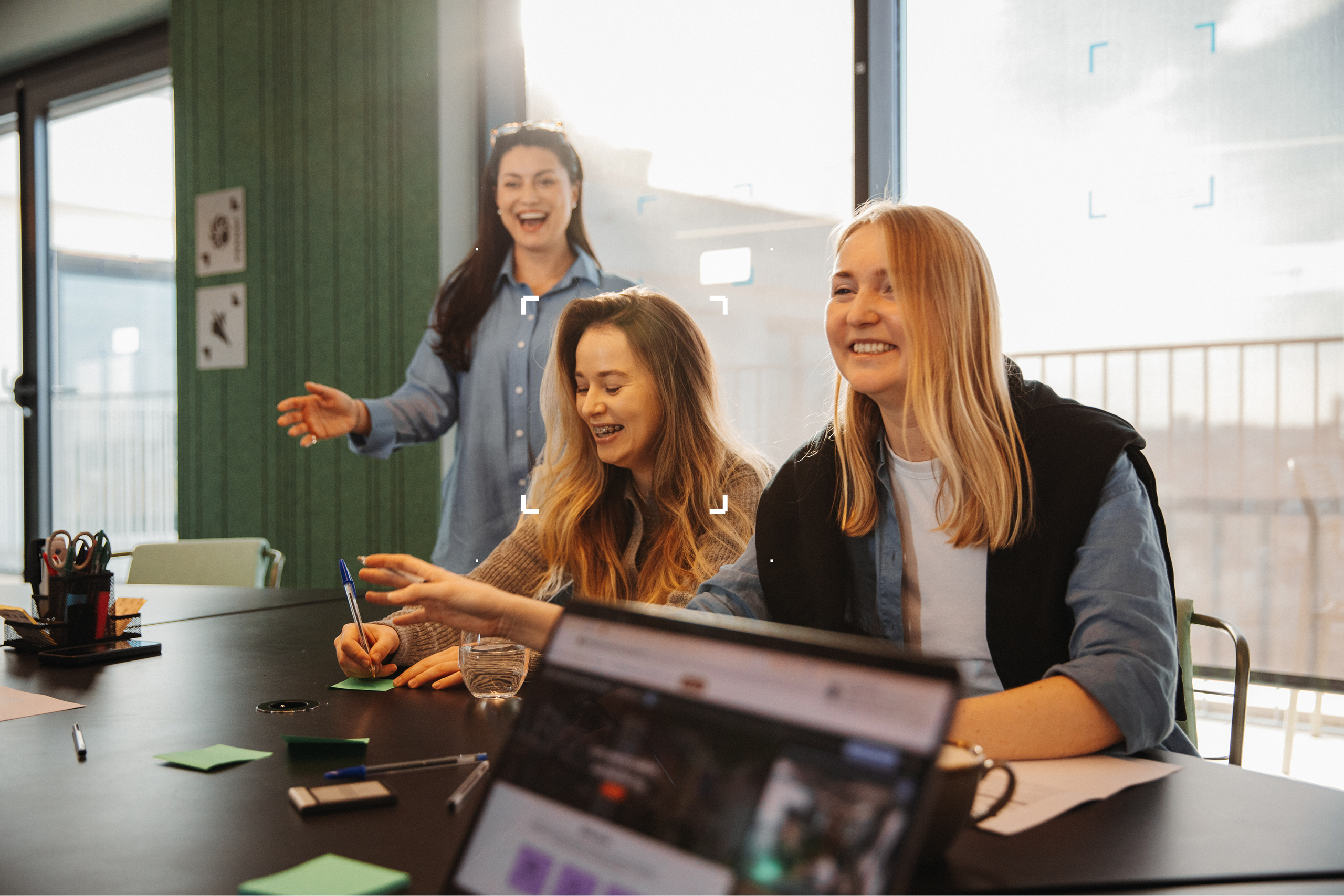 Group 1000002304 Three women smiling in front of a window with a laptop in front of them